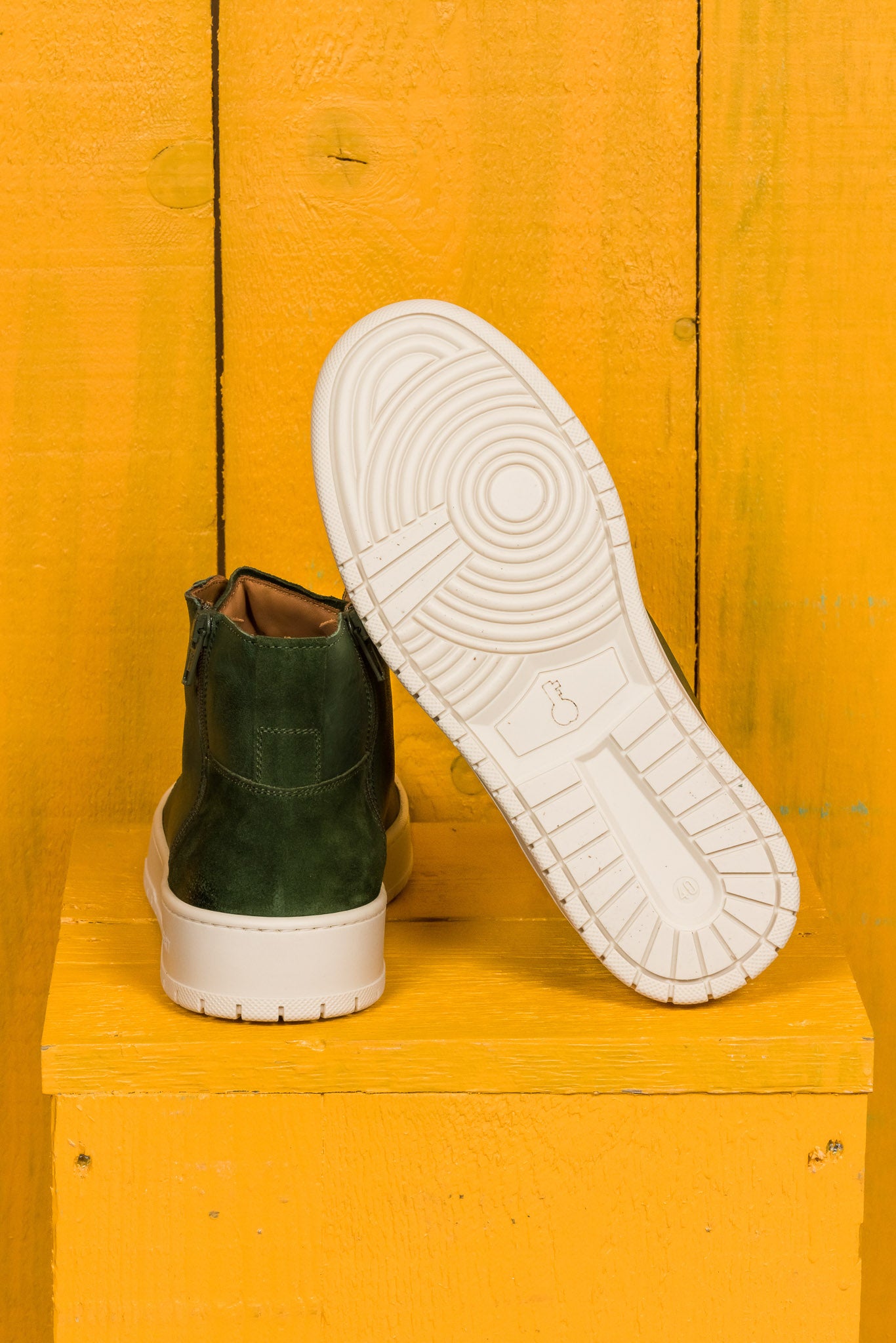 Rear view of one Bonetti 8473 unisex green leather high-top sneaker, while the other is angled to display the rubber sole.