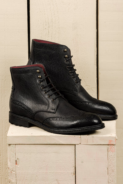 Side view of a pair of Benheart Daniel men’s black leather lace-up brogue ankle boots with wingtip design.