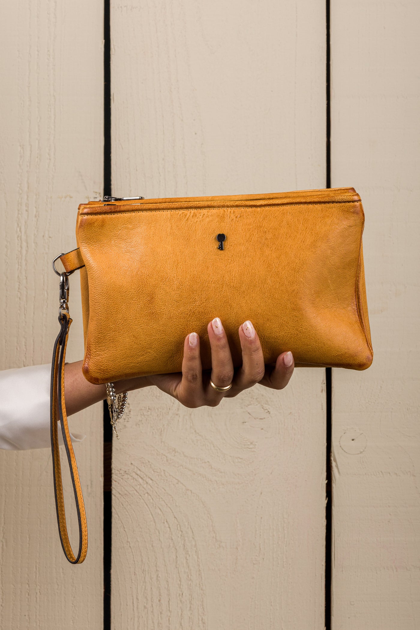 Front view of the Benheart Desert Pochette leather clutch in mahogany held in hand by a model, compact size, handcrafted in Italy.