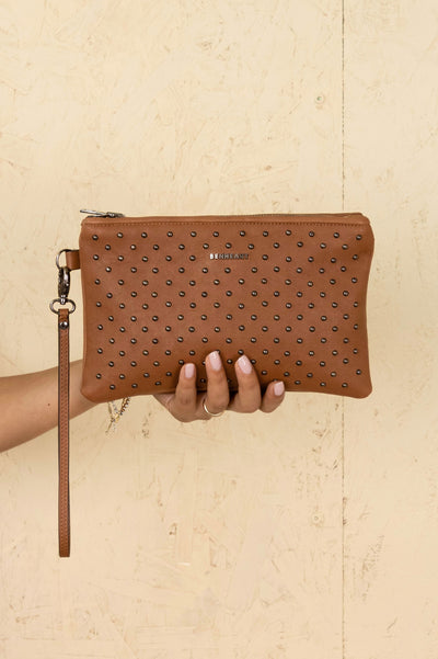 Front view of the Benheart Desert Pochette Borchiata in Cuoio color, handcrafted in Italy, held by a model.