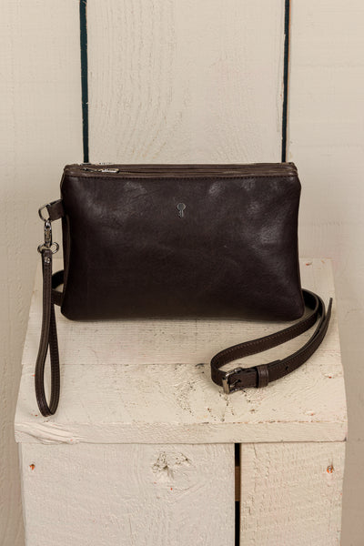 Front view of the Benheart Desert Pochette leather clutch in testa di moro dark brown, highlighting the two zippered compartments and adjustable shoulder strap.