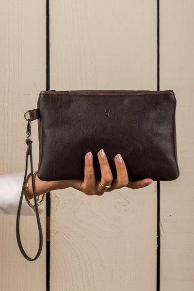 Front view of the Benheart Desert Pochette leather clutch in dark brown held in hand by a model, compact size, handcrafted in Italy.