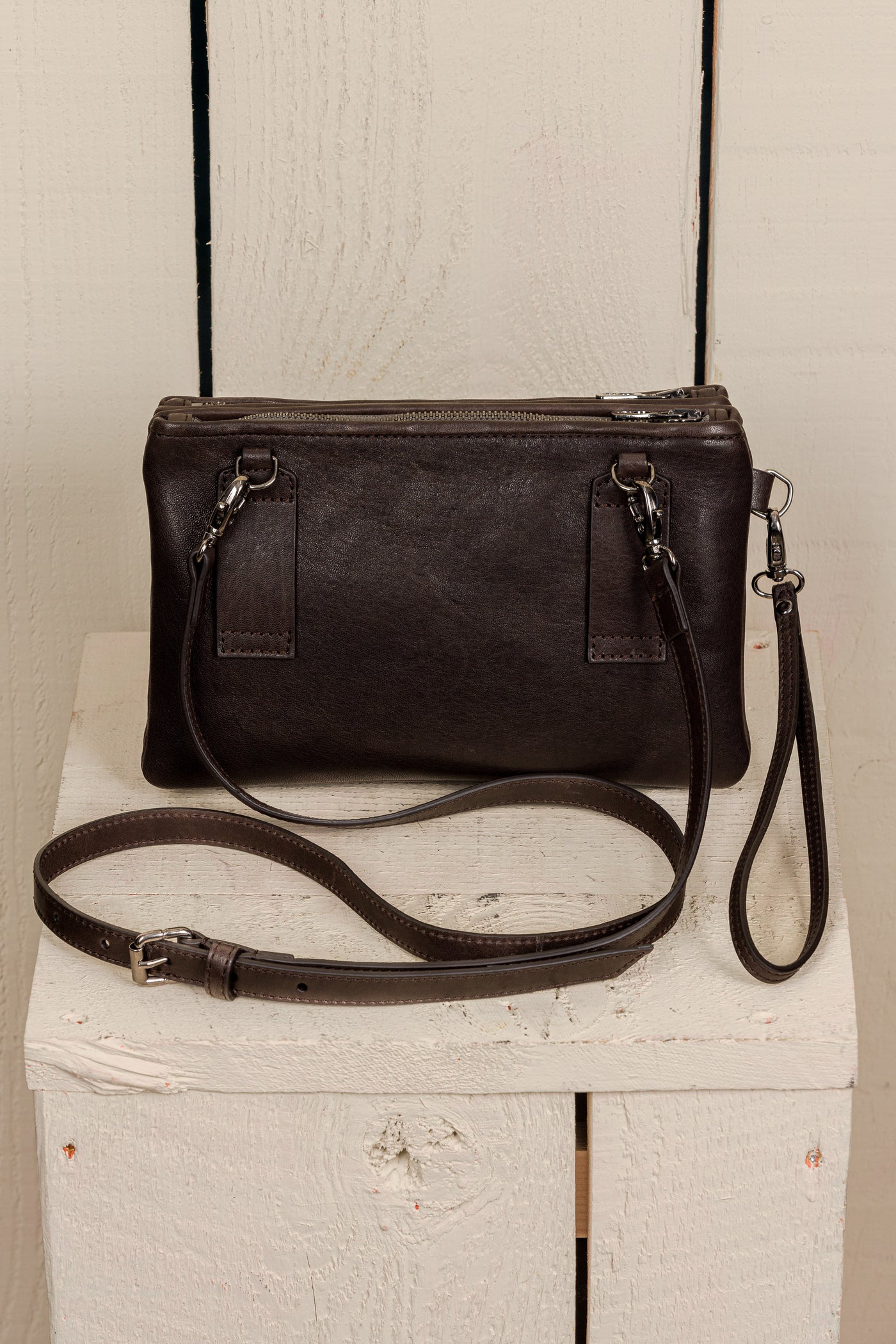 Back view of the Benheart Desert Pochette leather clutch in dark brown, showing the adjustable shoulder strap and smooth leather finish.