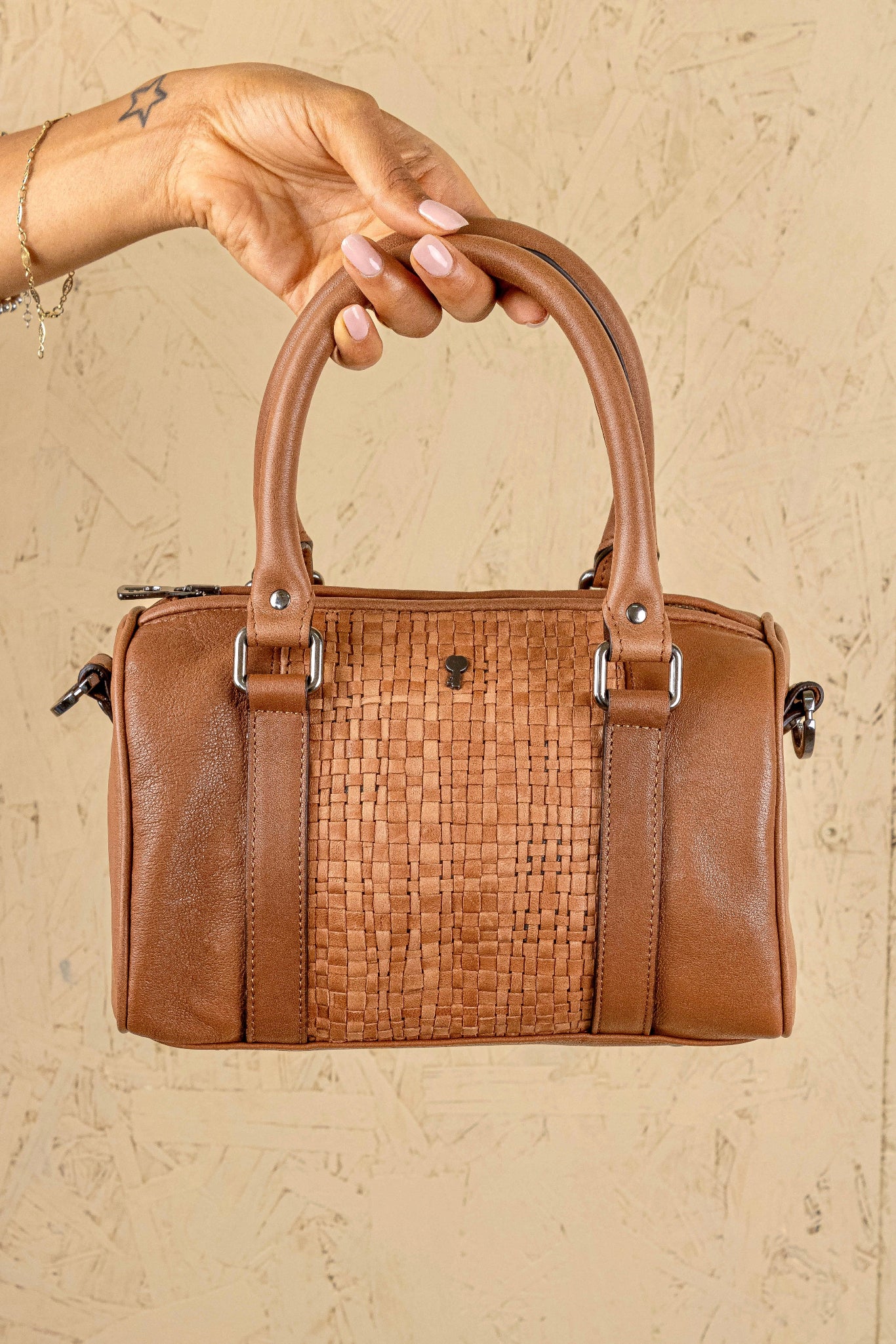Front view of Benheart Dom Intrecciata tan woven leather bag, held by model on handles, handcrafted in Florence.