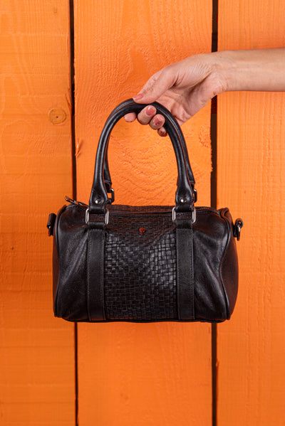 Front view of Benheart Dom Intrecciata black woven leather bag, held by model on handles, handcrafted in Florence.