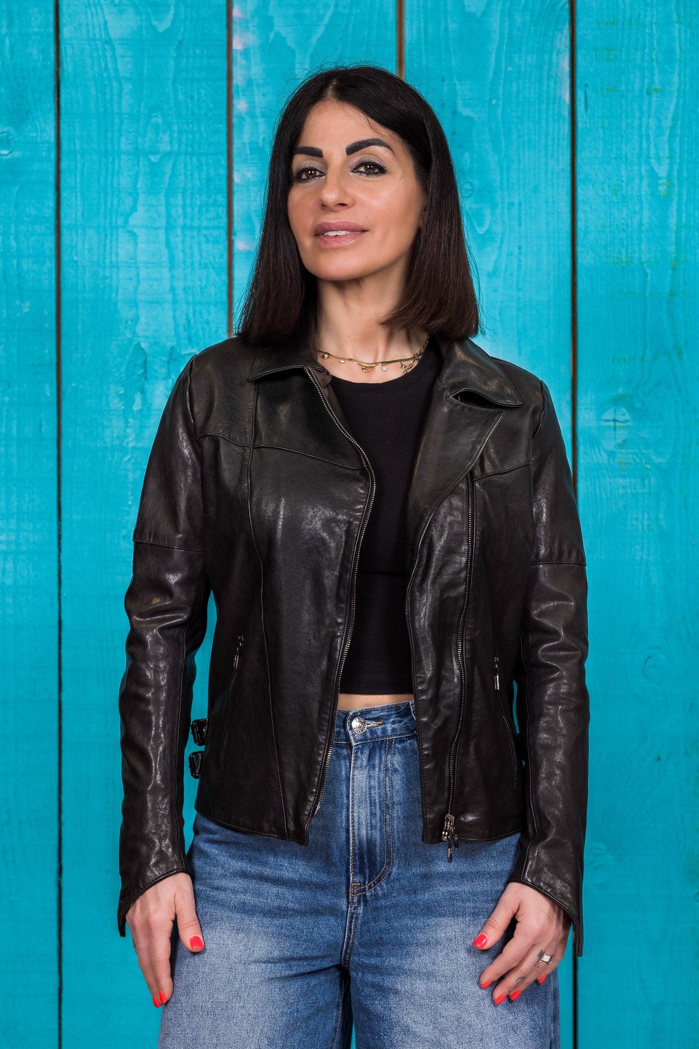 Model wearing Fede black women's leather biker jacket, open, front view.