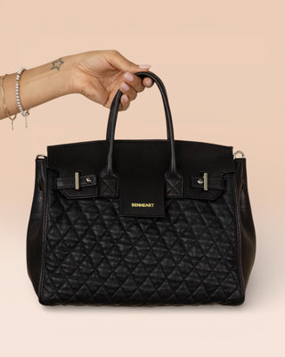 Ginevra Small Trapuntata women’s black quilted lamb leather handbag by Benheart, front view held by model by the handles.