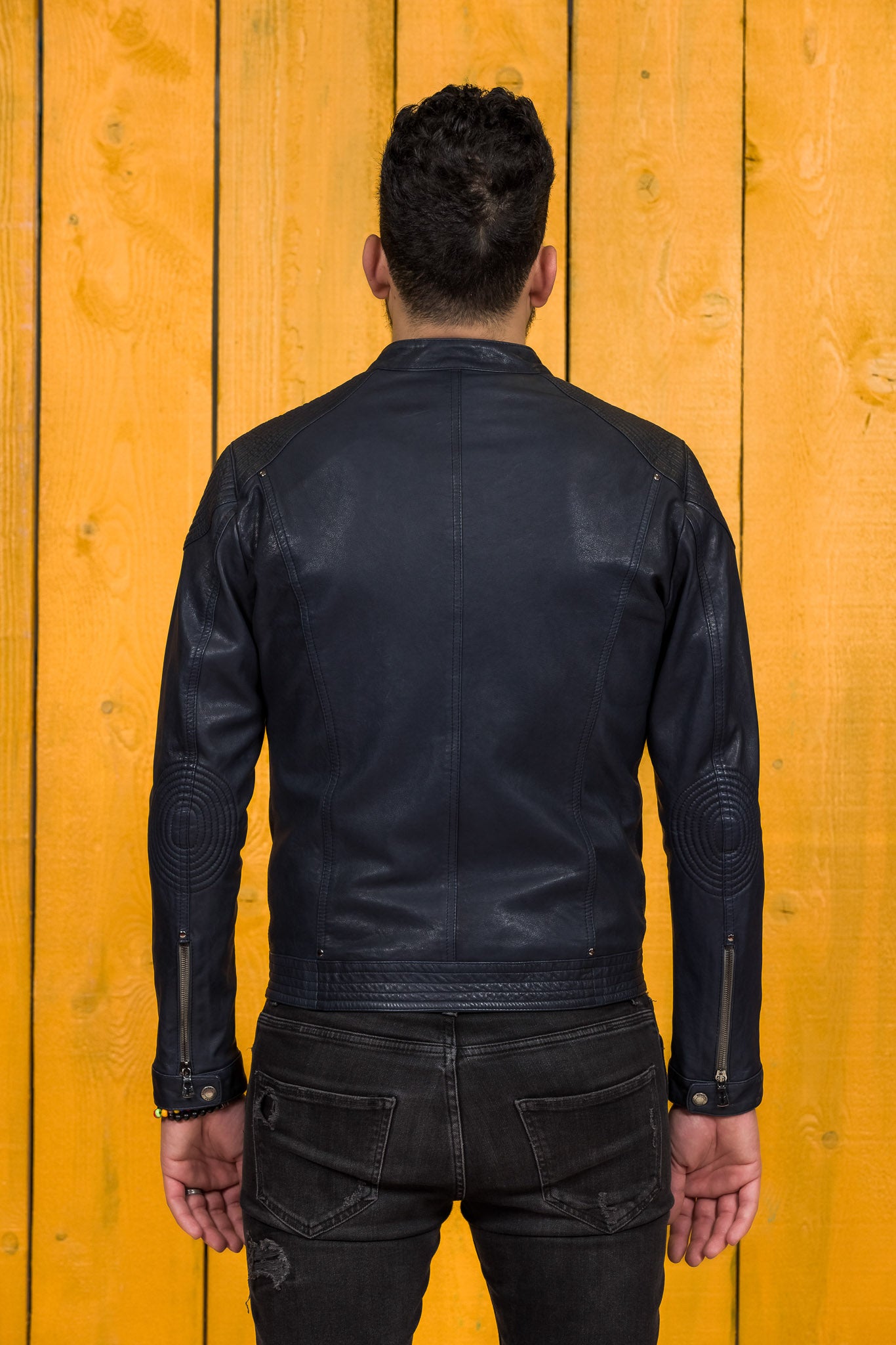 Back view of a model wearing the blue Hich leather jacket by Benheart.