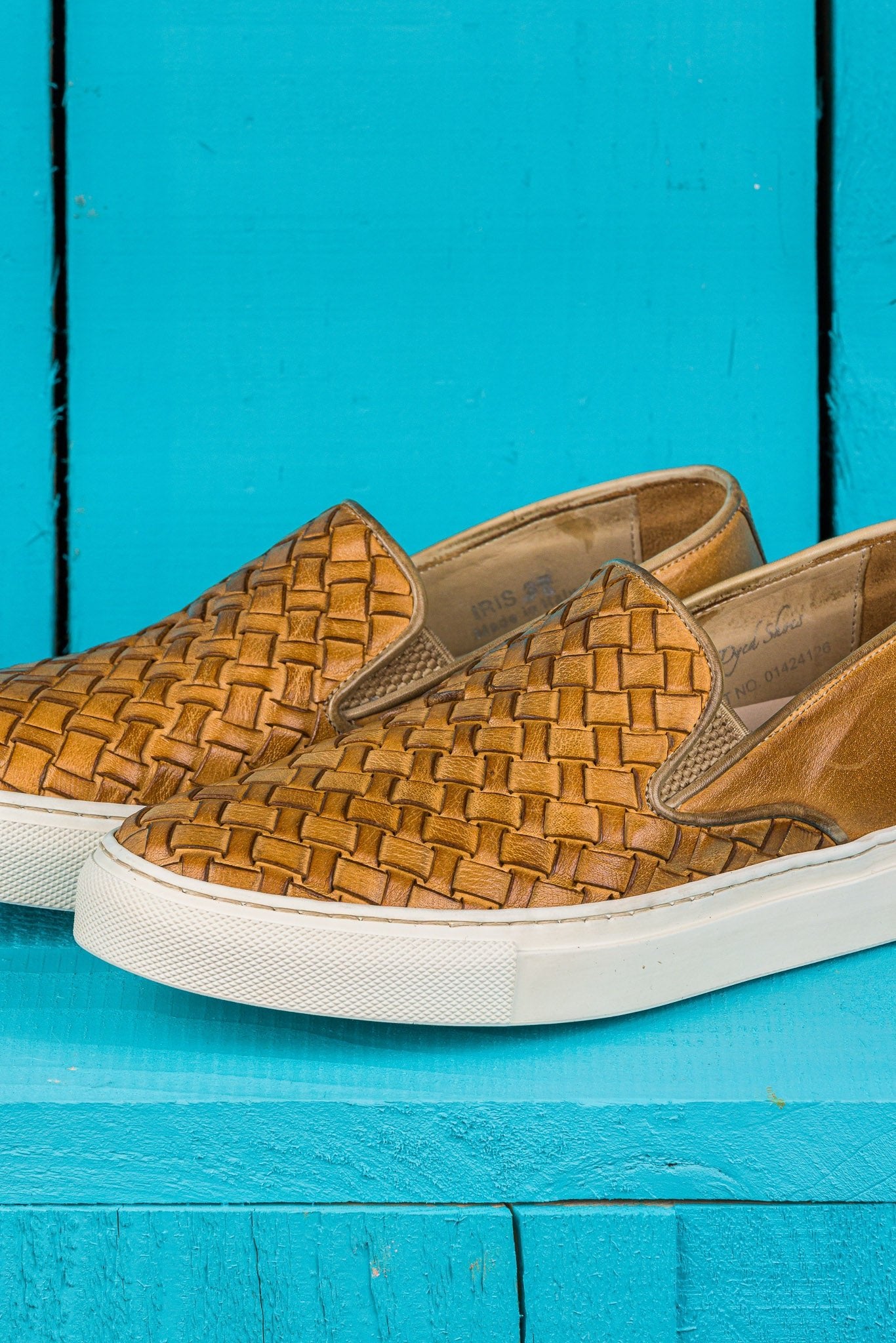 Close up view of Iris unisex woven slip-on shoes in mahogany leather with white rubber soles.