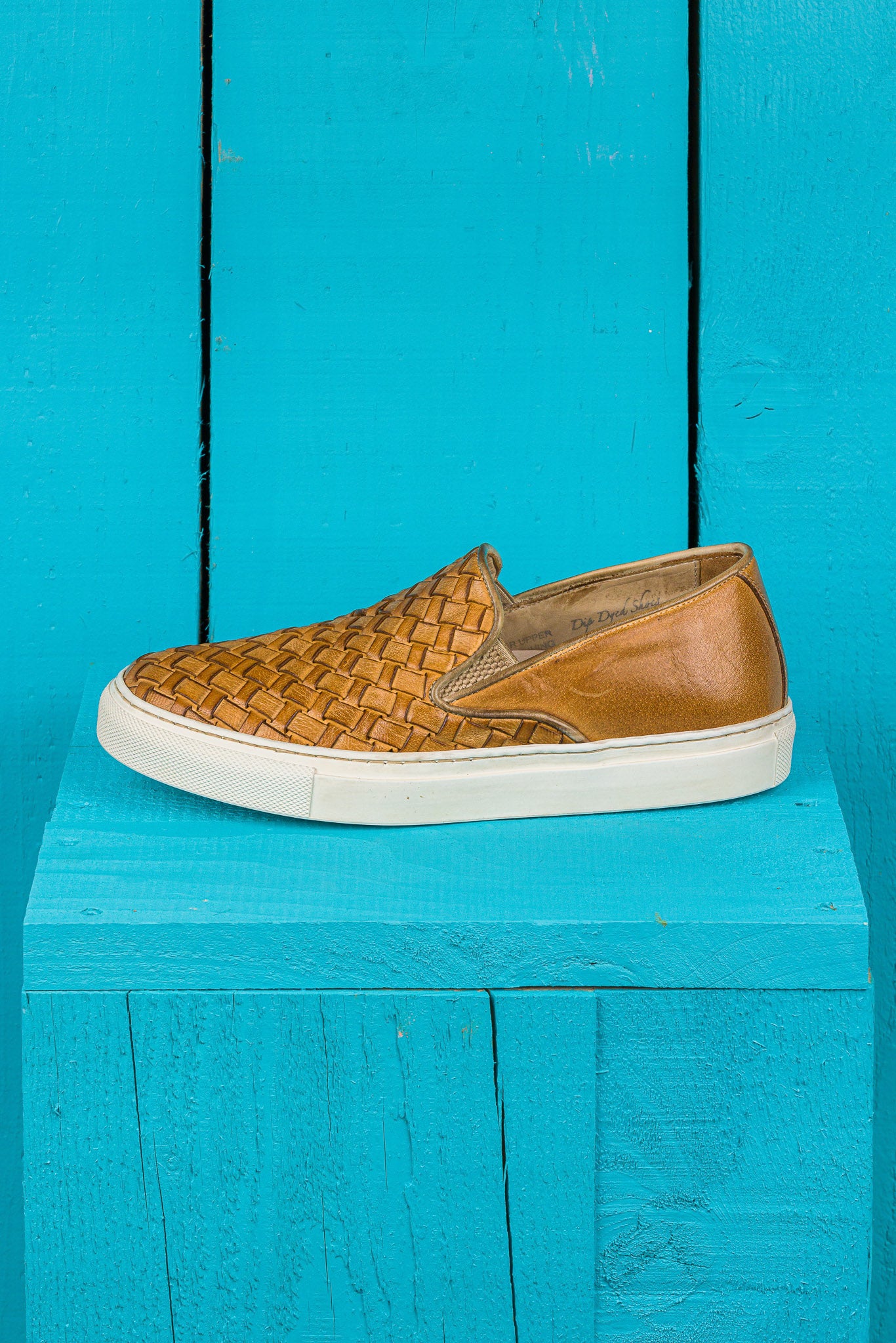Side view of Iris unisex woven slip-on shoes in mahogany leather with white rubber soles.