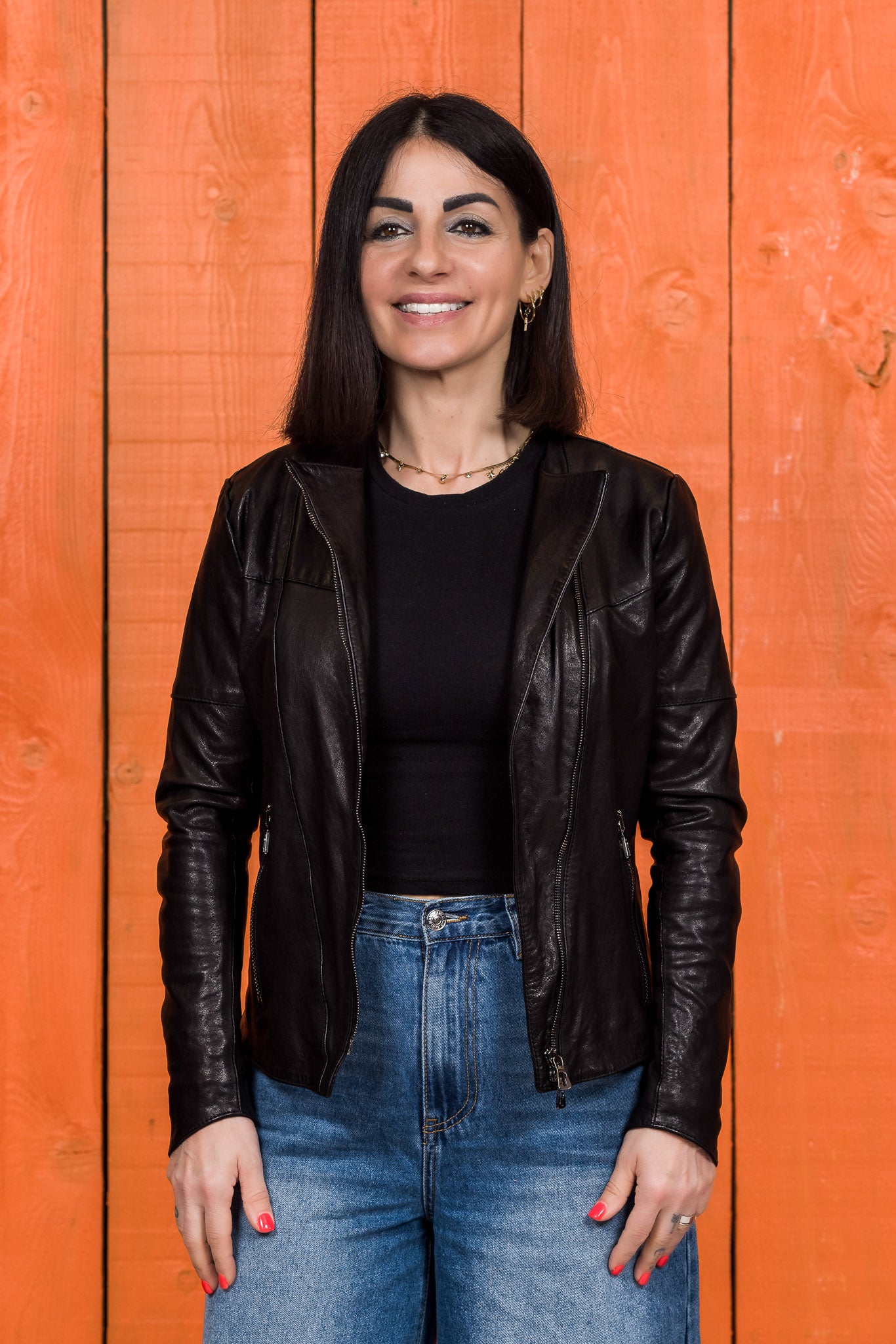 Front view of model wearing Jane women's black leather biker jacket, jacket open.