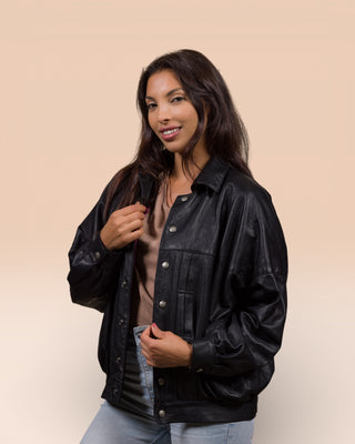 Slightly angled view of a model wearing the Jasmine oversized black leather jacket with the jacket open.