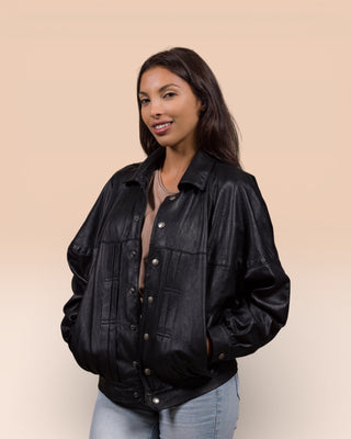 Slightly angled view of a model wearing the Jasmine oversized black leather jacket, mostly open with hands in pockets.