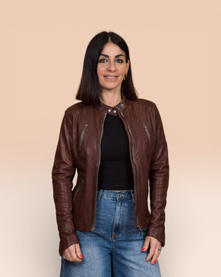 Front view of model wearing Lory women's brown leather biker jacket, jacket open, collar buttoned.