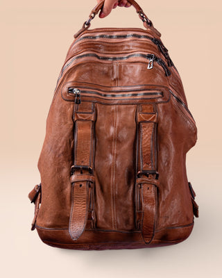 Model holding the Lorenzo unisex leather backpack in cuoio, handcrafted in Italy.