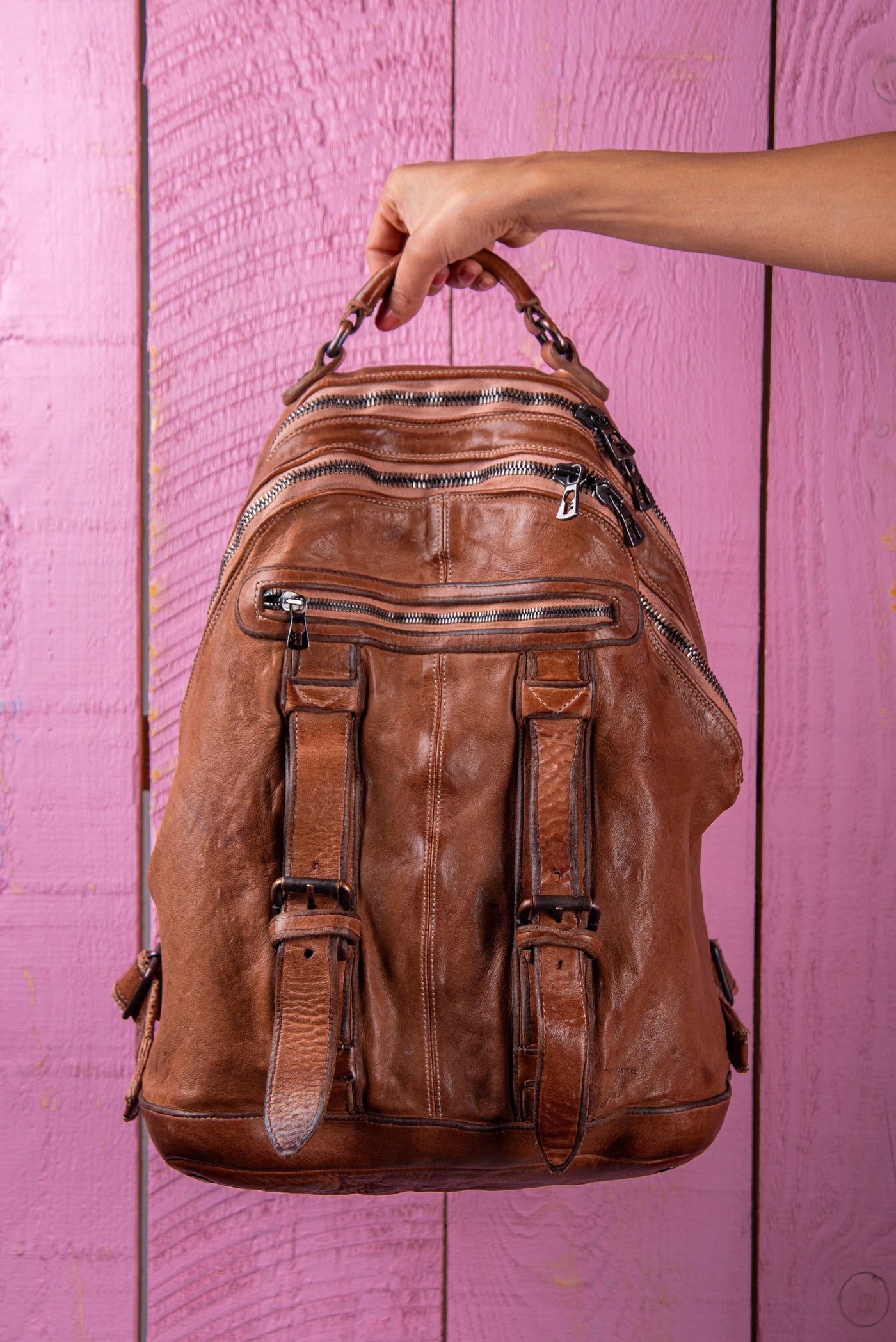 Model holding the Lorenzo unisex leather backpack in cuoio, handcrafted in Italy.