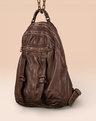 Three-quarter view of the Lorenzo unisex leather backpack in brown, showing front pockets and zipper details.