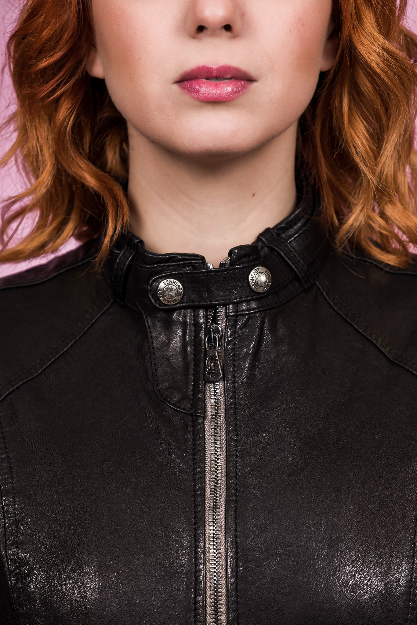Close-up of front zipper with Benheart logo and collar straps on Lucia women's black leather jacket.