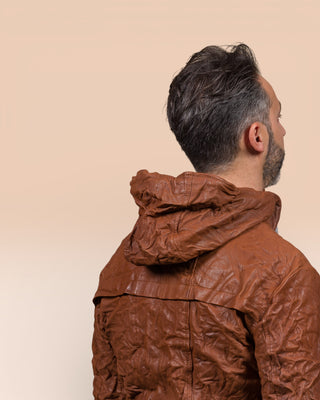 Detail of the model wearing the Michelangelo men's leather jacket in cognac, rear view highlighting the hood.