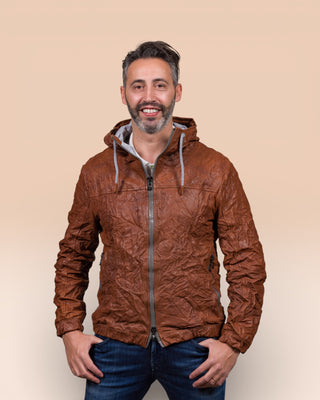 Back view of the Michelangelo men's leather jacket in cognac with hood, worn by the model with the collar open, showcasing its signature wrinkled leather finish.
