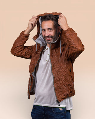 Angled view of the model wearing the Michelangelo men's leather jacket in cognac, shown with the jacket open while adjusting the hood.