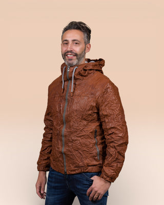 Front angled view of the Michelangelo men's leather jacket in cognac, worn closed by the model with one hand in the pocket.