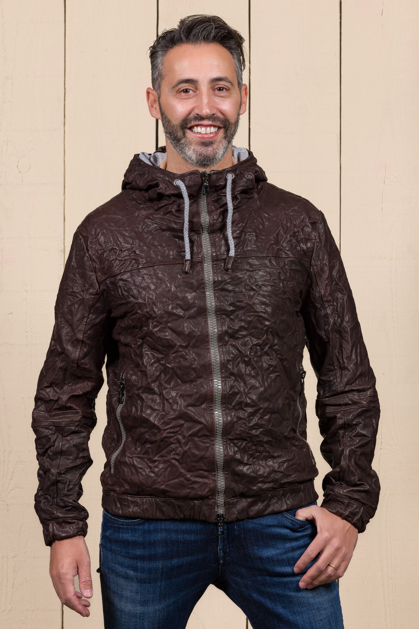 Model wearing a Michelangelo men's leather jacket with hood, in dark brown, handcrafted by Benheart in Florence, Italy.
