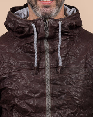 Detail of a model wearing the Michelangelo men's leather jacket in dark brown, featuring visible zippers and hood drawstrings.