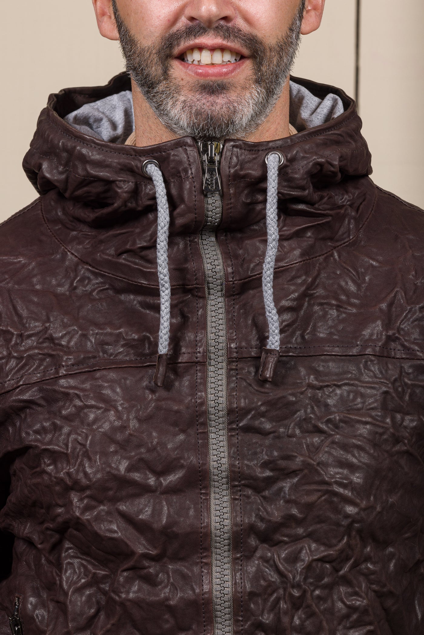 Detail of a model wearing the Michelangelo men's leather jacket in dark brown, featuring visible zippers and hood drawstrings.