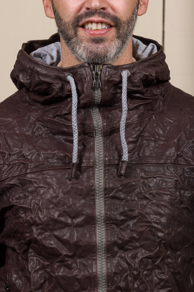 Detail of a model wearing the Michelangelo men's leather jacket in dark brown, featuring visible zippers and hood drawstrings.