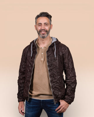 Model wearing a Michelangelo men's leather jacket with hood, in dark brown, handcrafted by Benheart in Florence, Italy, with the jacket open.