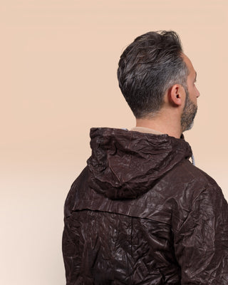 Detail of the model wearing the Michelangelo men's leather jacket in dark brown, rear view highlighting the hood.