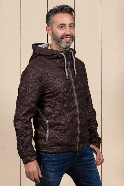 Angled view of a model wearing the Michelangelo men's leather jacket in dark brown, with the collar open, featuring visible zippers and hood drawstrings.