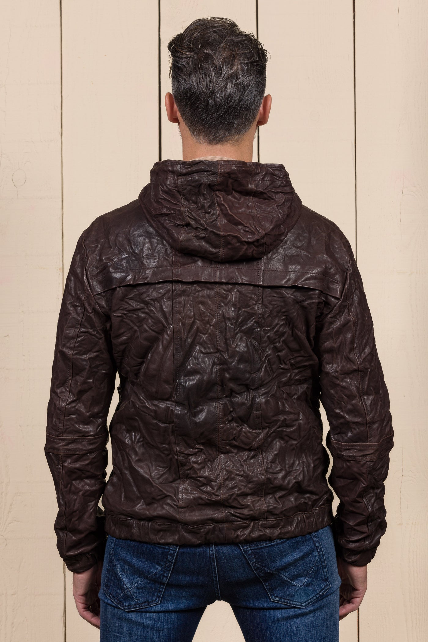 Back view of a model wearing the Michelangelo men's leather jacket in dark brown, with hood, featuring Benheart’s signature handcrafted wrinkled finish.