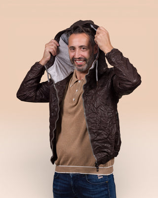Angled view of the model wearing the Michelangelo men's leather jacket in dark brown, shown with the jacket open while adjusting the hood.