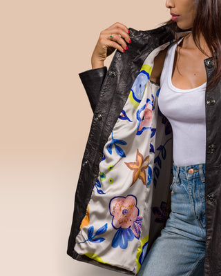 Close-up of a model holding the Mini black leather jacket open to reveal the inner lining.