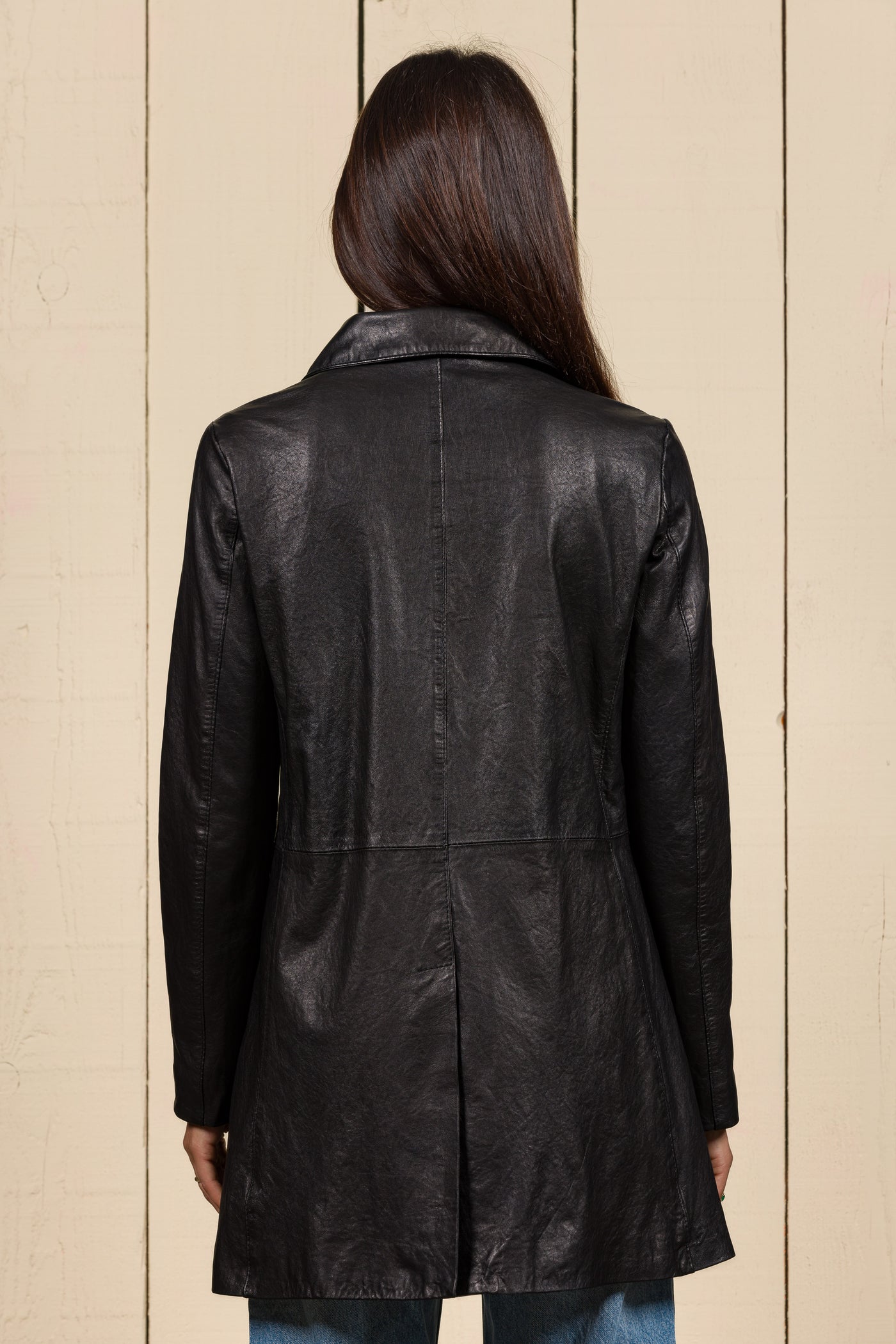 Rear view of a model wearing the Mini black leather jacket for women, handcrafted in Florence, Italy.