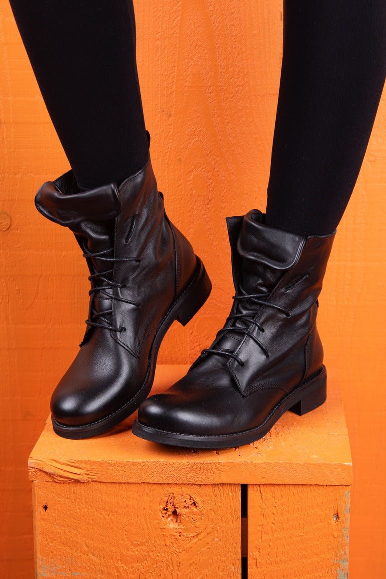 Front angled view of a model wearing Phantom black leather lace-up boots.