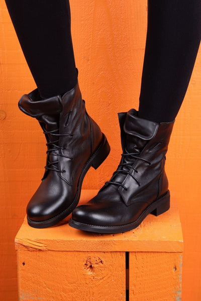 Front angled view of a model wearing Phantom black leather lace-up boots.