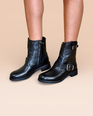 Side angled view of model wearing Benheart Pre08F black leather ankle boots with buckles.