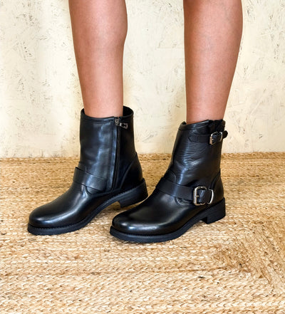 Side angled view of model wearing Benheart Pre08F black leather ankle boots with buckles.