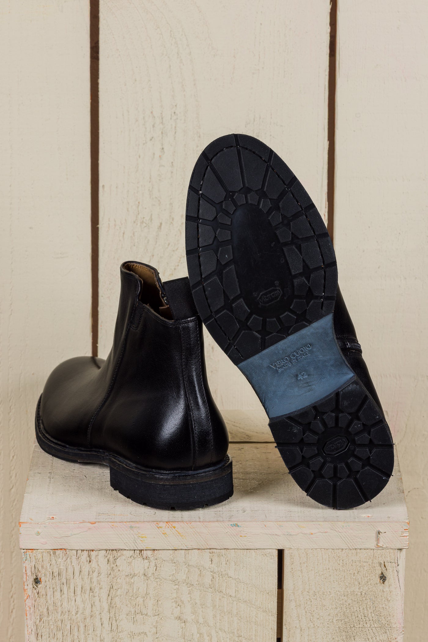 Rear view of Suso black leather Chelsea boots, one turned to show Vibram soles.