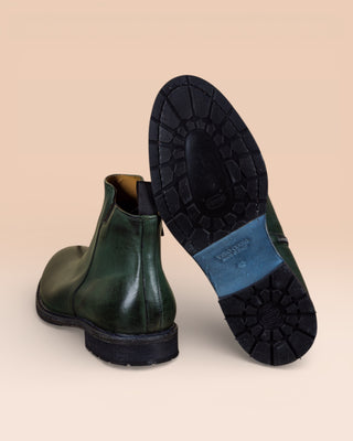 Rear view of Suso green leather Chelsea boots, one turned to show Vibram soles.