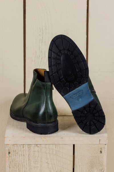 Rear view of Suso green leather Chelsea boots, one turned to show Vibram soles.