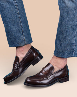 Model wearing a pair of Benheart Toro Penny Loafers in polished cordovan leather, dark brown testa di moro.