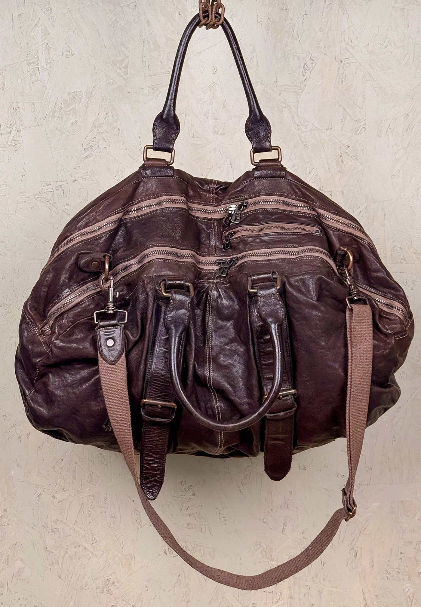 Angled front and top view of the Benheart Viaggio unisex brown leather travel bag, showing multiple zippers, handles