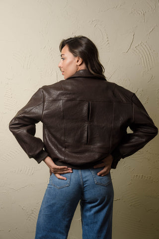 Hajar dark brown leather bomber jacket worn open over a white top