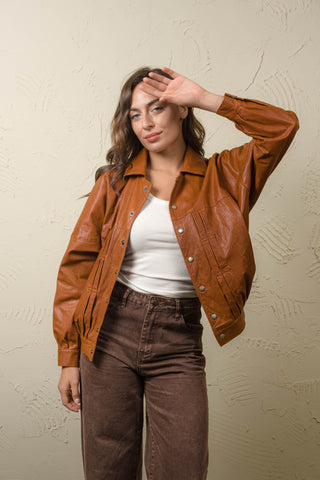 Jasmine oversized cognac leather jacket worn open with the arm raised, showing the relaxed sleeve