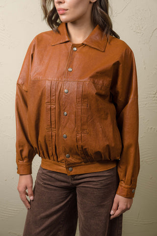 Close-up of the Jasmine cognac leather jacket closed, showing pleated chest stitching and BENHEART snap buttons