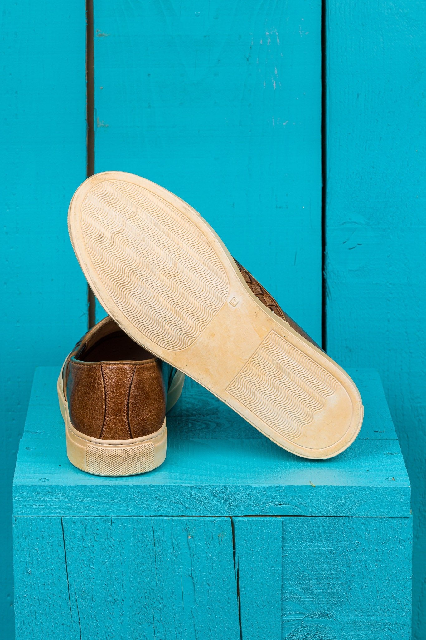 Rear view of Benheart Iris woven cerro leather slip-on shoes, one showing the heel and the other the rubber sole.